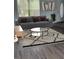 A staged living room with gray walls, a gray sofa with pillows, and a glass coffee table on a patterned rug at 1117 Cambourne Dr, Kissimmee, FL 34758