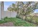 A fenced backyard, featuring a mixture of green vegetation and leaves, with a large tree in the background at 1209 S Station Pl # 306, Orlando, FL 32809