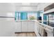 White kitchen with stainless steel appliances, wood floors, and a view to the outside at 140 Coco Plum, Davenport, FL 33897