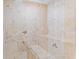 Modern shower with neutral colored stone walls and two built-in seating areas at 140 Coco Plum, Davenport, FL 33897