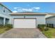 Detached one-car garage with a white door and brick paver driveway, framed by green bushes and a blue sky at 14218 Lanikai Beach Dr, Orlando, FL 32827