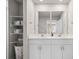 Bright bathroom with double sinks, white cabinets, large mirror, and storage shelves for convenience at 2052 Milkweed St, Ocoee, FL 34761