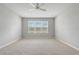 Empty bedroom showcases neutral carpeting, a ceiling fan, and a large window for natural light at 2282 Kaley Ridge Rd, Clermont, FL 34715