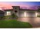 Beautiful single-Gathering home featuring a three-car garage, lush lawn, and paver driveway with attractive landscaping at 2282 Kaley Ridge Rd, Clermont, FL 34715