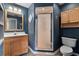 Bathroom with blue walls, a wood vanity, a framed mirror, and a glass door shower at 26 Backspin Ln, Orlando, FL 32804