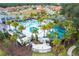Aerial view of community pool with water slide, palm trees, lounge chairs, and lush landscaping at 2613 Santosh Cv, Kissimmee, FL 34746