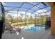Screened-in pool with lounge chairs overlooking a serene pond and lush greenery at 2613 Santosh Cv, Kissimmee, FL 34746