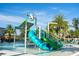 Community water park featuring a blue water slide, palm trees, and lounge chairs for residents to enjoy on a sunny day at 2613 Santosh Cv, Kissimmee, FL 34746