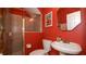 Red bathroom with tiled shower behind glass doors, toilet, and single sink at 4527 Sunset Ln, Oviedo, FL 32765