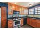 Modern kitchen with stainless steel appliances, wood cabinets, granite countertops, and a tile backsplash at 501 Sheridan Blvd, Orlando, FL 32804