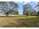 A large front yard with shade trees, a street in the background, and power lines in the sky at 5150 Old Howell Branch Rd, Winter Park, FL 32792