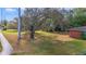 Lush front yard with mature tree providing shade, a glimpse of the red brick exterior at 5150 Old Howell Branch Rd, Winter Park, FL 32792