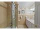 Bathroom with beige tile, floral wallpaper, and a glass-enclosed shower at 5203 Pineview Way, Apopka, FL 32703