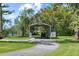 View of a circular driveway with a covered carport, accented with a red and white star decoration, in a grassy yard at 5203 Pineview Way, Apopka, FL 32703