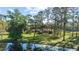 Spacious lot with mature trees and view of the brick home from across the lake, reflecting in the clear water at 5203 Pineview Way, Apopka, FL 32703