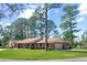 Brick house with an attached garage, covered front porch with rocking chairs and expansive front lawn with mature trees at 5203 Pineview Way, Apopka, FL 32703