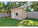 Weathered shed is in a fenced yard with an overgrown canopy of trees looming over it at 5715 Satel Dr, Orlando, FL 32810