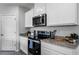 Close up on the modern kitchen appliances and granite countertops with sleek white cabinets and black oven at 1815 Waggoner St, Kissimmee, FL 34744