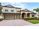 Elegant two-story home boasting a well-maintained lawn, brick driveway, and a welcoming front entrance at 2829 Autumn Breeze Way, Kissimmee, FL 34744
