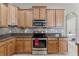 Close-up of kitchen featuring stainless steel stove, granite countertop, decorative backsplash and wood cabinetry at 2829 Autumn Breeze Way, Kissimmee, FL 34744
