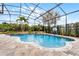 Spacious screened-in pool area featuring lush landscaping, a stone waterfall, and a basketball hoop at 2829 Autumn Breeze Way, Kissimmee, FL 34744