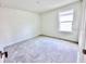 Clean, empty bedroom with neutral-toned carpet and walls and a window to provide natural light at 3171 Cup Dr, Lakeland, FL 33803