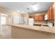 Open-concept kitchen with wood cabinetry, white appliances, and a breakfast bar overlooking the living area at 3176 Feltrim Pl # 205, Kissimmee, FL 34747