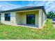 View of the rear of the house featuring a sliding glass door and a covered patio area surrounded by a green lawn at 3225 Cup Dr, Lakeland, FL 33803