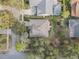 An aerial view of a well-maintained house with a neutral roof and well-manicured lawns with mature trees and a nearby community pool at 325 Bellingrath Terrace, Deland, FL 32724