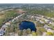 An aerial view of a neighborhood with a large pond, surrounded by mature trees and various homes at 325 Bellingrath Terrace, Deland, FL 32724