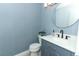 Updated half bathroom features a modern vanity with granite countertop and stylish round mirror at 5136 Stratemeyer Dr, Orlando, FL 32839
