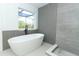 Modern bathroom featuring a standalone tub, gray accent wall, and bright natural light from large window at 5136 Stratemeyer Dr, Orlando, FL 32839