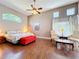 Bright main bedroom with a ceiling fan, red bench, wood floors, and large windows at 777 Crepe Myrtle Cir, Apopka, FL 32712