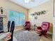 Sitting area with large window, ceiling fan, light walls, hardwood floors and red leather chairs at 777 Crepe Myrtle Cir, Apopka, FL 32712