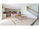 Open dining area with a wood table, stainless steel bench, and a colorful rug, next to the modern kitchen and stairs at 8231 Chilton Dr, Orlando, FL 32836