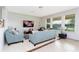 Bright living room with blue sofas, large windows overlooking the backyard, and a modern entertainment center at 8231 Chilton Dr, Orlando, FL 32836