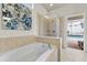 Soaking tub in the bathroom with a glass-enclosed shower and backyard views at 9026 Rhodes St, Kissimmee, FL 34747