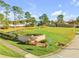 The community entrance features a sign with lush landscaping, green grass, and a pond at 114 Tuscany Villas Dr, Edgewater, FL 32141