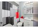 Compact bathroom featuring a sink, toilet, and shower with a black, white, and red patterned shower curtain at 1170 Calle Del Rey # D, Casselberry, FL 32707
