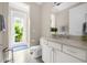 Bright bathroom with a white vanity, marble countertop, and a view of the lush greenery outside at 1432 Titian Ct, Reunion, FL 34747