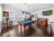Spacious game room with a pool table, bar, tv, multiple windows and dark wood floors at 1432 Titian Ct, Reunion, FL 34747