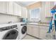 Well-equipped laundry room featuring a washer, dryer, and ample cabinet space above the sink at 1432 Titian Ct, Reunion, FL 34747