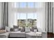 Cozy living area featuring a plush sectional sofa, large windows with sheer curtains, and serene neighborhood views at 1432 Titian Ct, Reunion, FL 34747