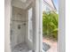 Modern glass-enclosed shower with tiled walls and a view of the tropical foliage outside at 1432 Titian Ct, Reunion, FL 34747