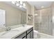Bathroom featuring double sinks and granite counters, plus a walk-in shower with glass door at 15489 Honeybell Dr, Winter Garden, FL 34787