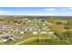 Aerial view of a residential neighborhood with modern homes, green lawns, and nearby fields at 16413 Bloom Ct, Groveland, FL 34736