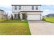 Traditional two-story home with an attached garage, green lawn, and a welcoming entrance pathway at 16413 Bloom Ct, Groveland, FL 34736