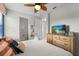 Cozy bedroom featuring a wooden dresser, mounted TV, and a view of the adjoining bathroom at 1841 Sawyer Palm Pl, Kissimmee, FL 34747