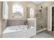 Relaxing bathroom featuring a tiled jacuzzi tub and separate glass shower with neutral paint at 2214 Windcrest Lake Cir, Orlando, FL 32824