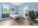 Light blue bedroom with a window, laminate flooring, a bed, and a door leading to a bathroom at 2214 Windcrest Lake Cir, Orlando, FL 32824